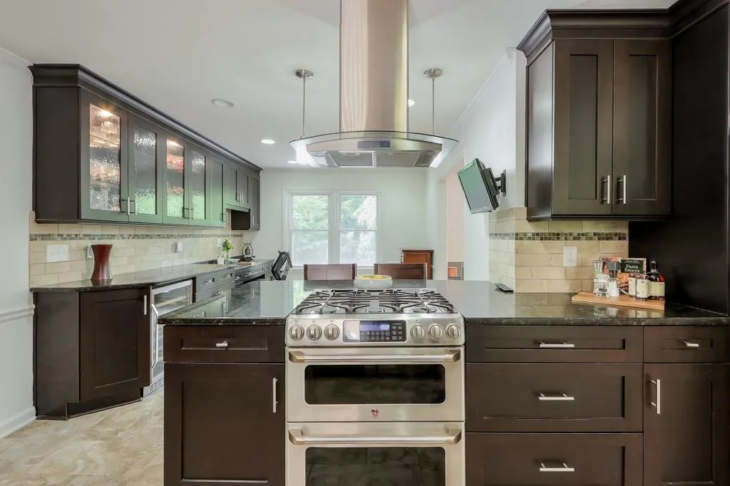 Kitchen featuring stainless steel gas range, granite countertops, and a range hood