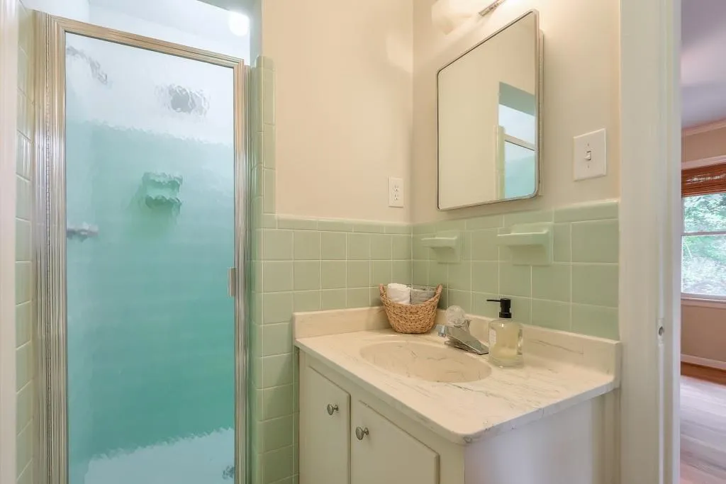 Bathroom featuring walk in shower, vanity, tile walls, backsplash, and hardwood / wood-style flooring