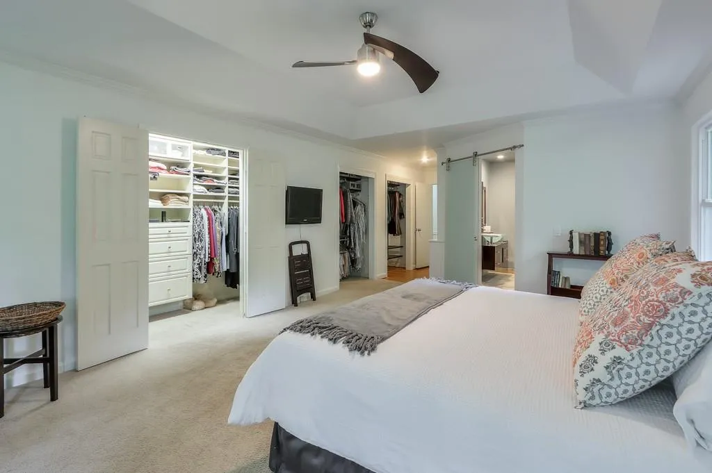 Owner's suite with Carpet and a spacious walk in closet, ceiling fan, a barn door, a raised ceiling, and ensuite bathroom