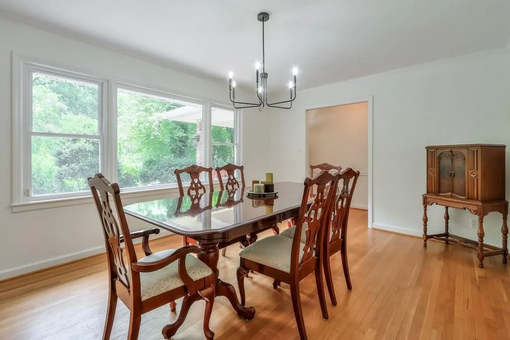 Dining space with a chandelier, light wood-type flooring, crown molding, and a healthy amount of sunlight