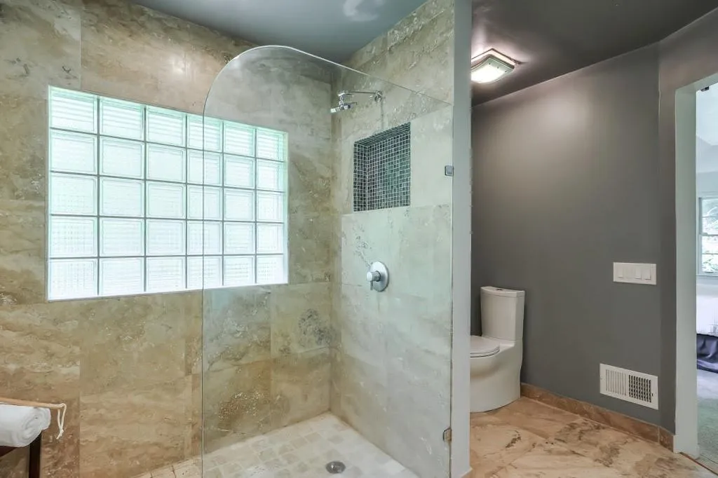 Bathroom with a tile shower, tile floors and plenty of natural light