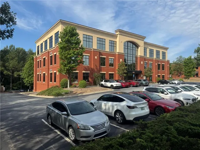Brick exterior with a stone-finish upper level, arched window entrance, and ample paved parking