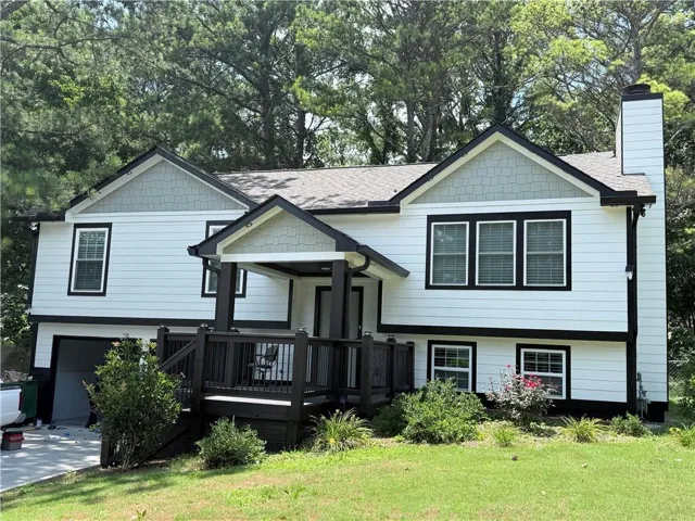 Split-level residence featuring white siding with black trim accents and a black-painted front porch