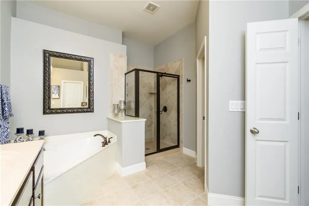 Bathroom featuring vanity, a stall shower, a garden tub, and light tile patterned flooring