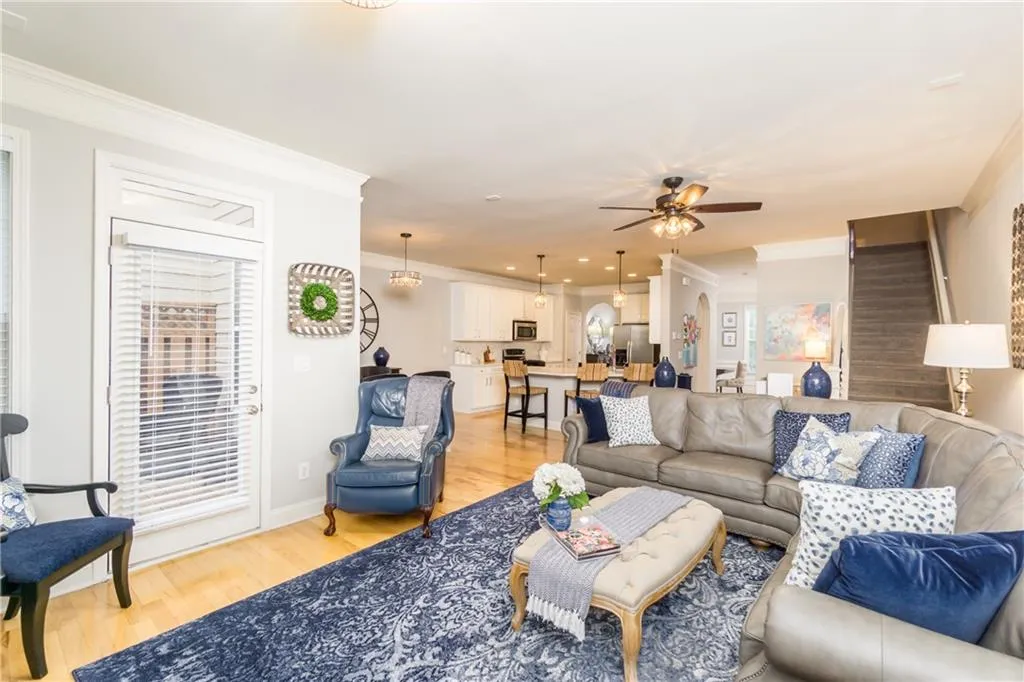 Living room with light wood-type flooring, crown molding, stairs, and a ceiling fan