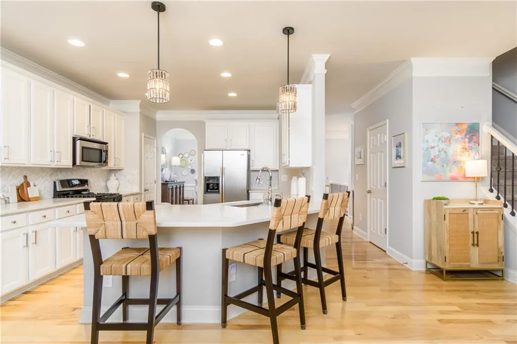 Kitchen featuring backsplash, appliances with stainless steel finishes, light wood finished floors, arched walkways, and a breakfast bar area