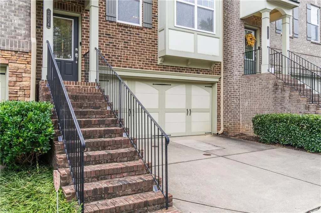 Entrance to property with a garage, driveway, and brick siding