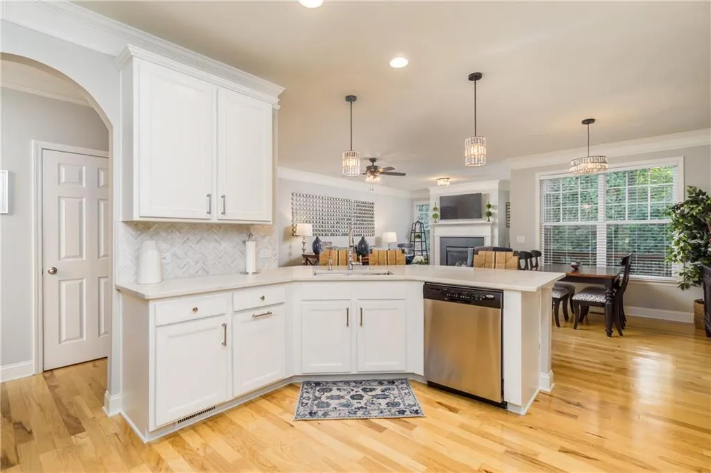 Kitchen with white cabinets, a peninsula, crown molding, stainless steel dishwasher, and pendant lighting