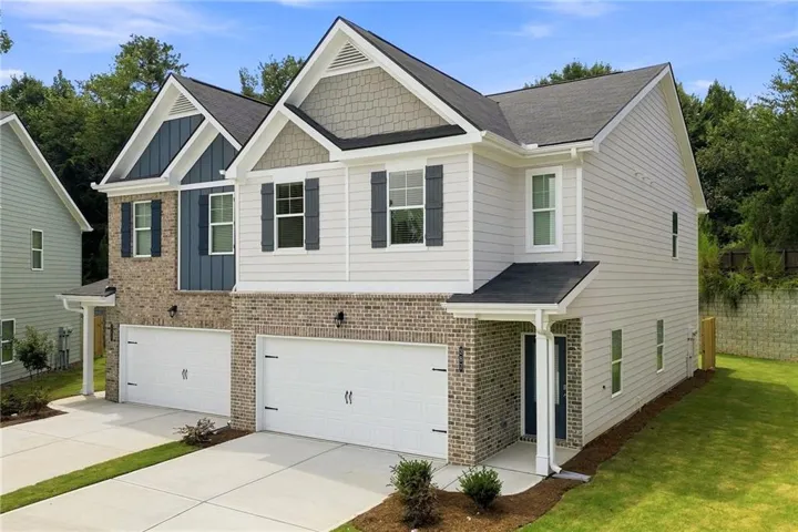 Two-story dwelling with brick and siding exterior, multiple gables, front-facing garages, and a concrete driveway