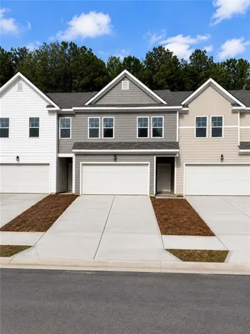Newly constructed townhomes featuring multi-toned siding, attached garages, multiple windows, and concrete driveways