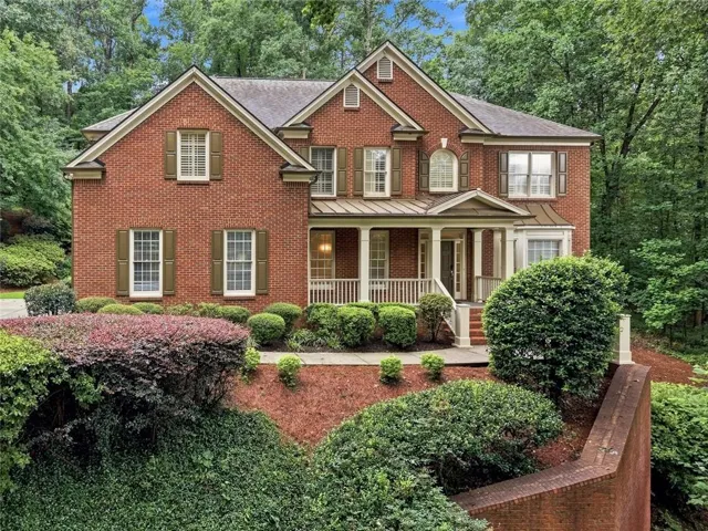 Traditional-style brick residence featuring a covered front porch with white columns and railing