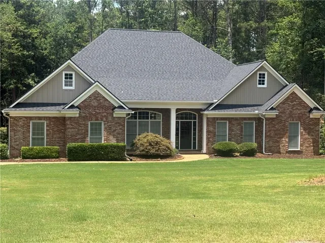 Brick exterior with tan siding accents, featuring a prominent front entrance with dual columns