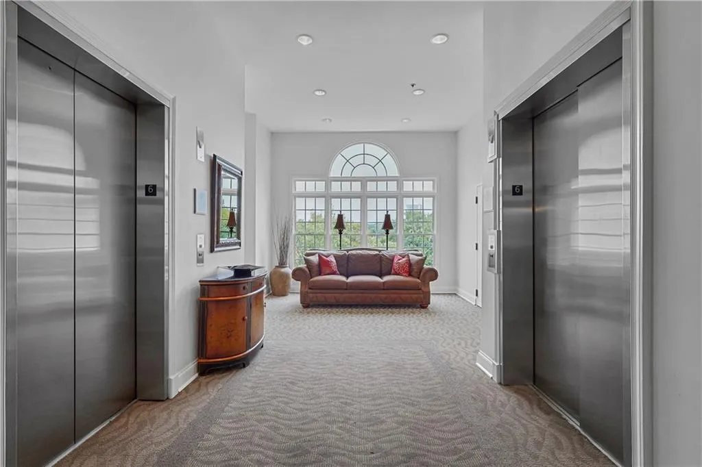 Hallway with elevator, light colored carpet, and recessed lighting