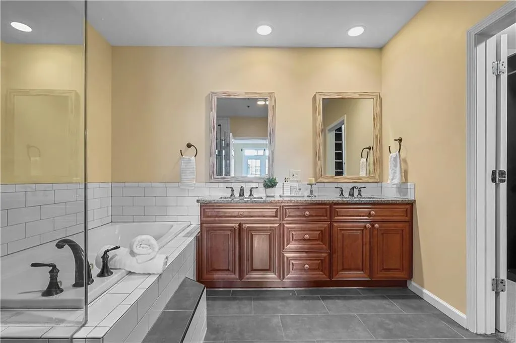 Bathroom with a bath, double vanity, dark tile patterned floors, and recessed lighting