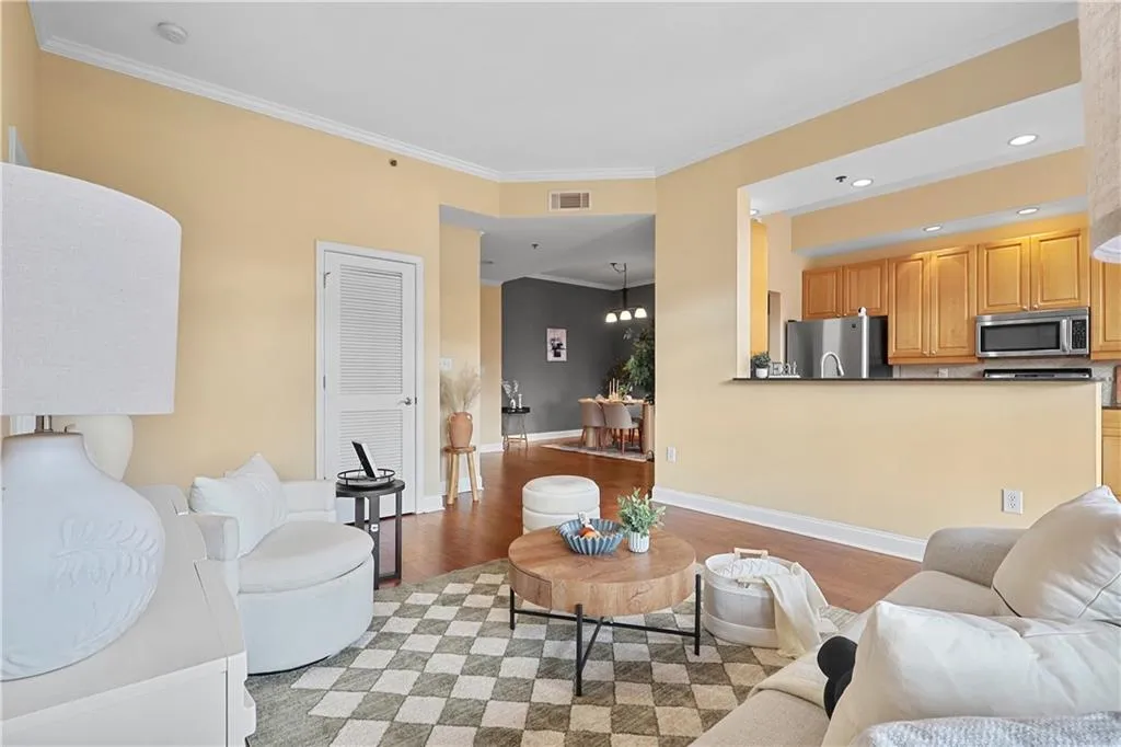 Living room with ornamental molding, a chandelier, light wood-style floors, and recessed lighting