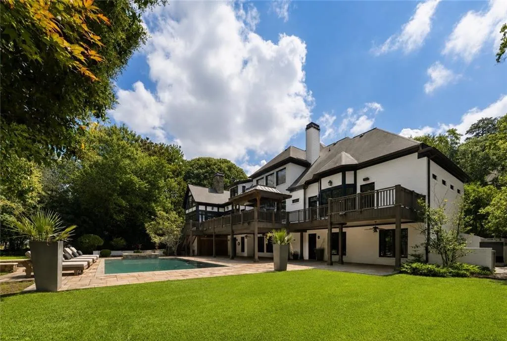 Expansive lawn with a rectangular swimming pool, stone paver patio, multi-level exterior decks, and mature perimeter trees