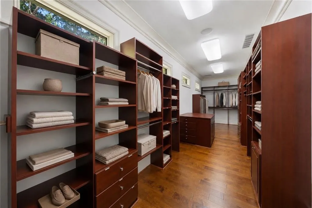 Custom closet system featuring wood-finish flooring, built-in shelving, integrated drawers, and garment rods