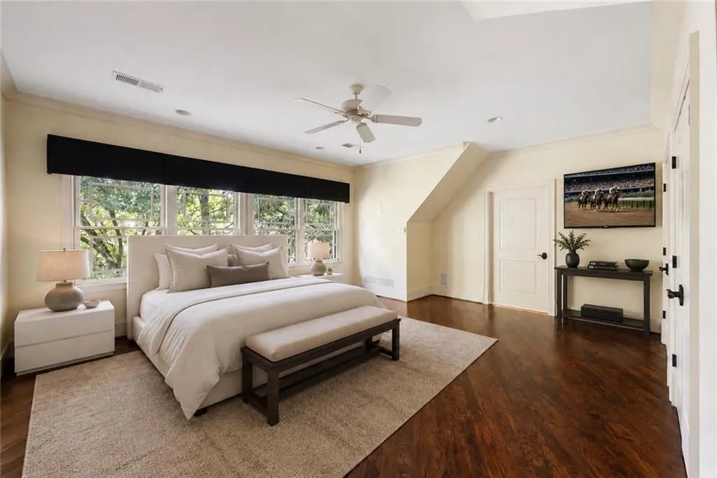 Wood-finish flooring, multiple windows with transom details, a ceiling fan, and painted interior doors with dark hardware
