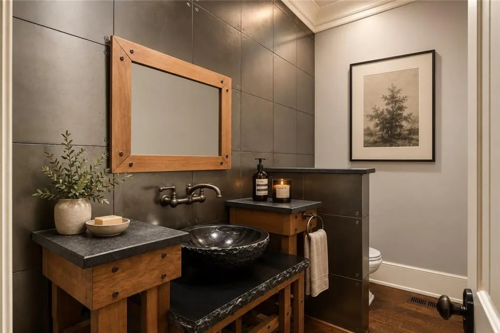 Powder room featuring metal wall paneling, a wood-framed mirror, a vessel sink, and a wall-mounted faucet