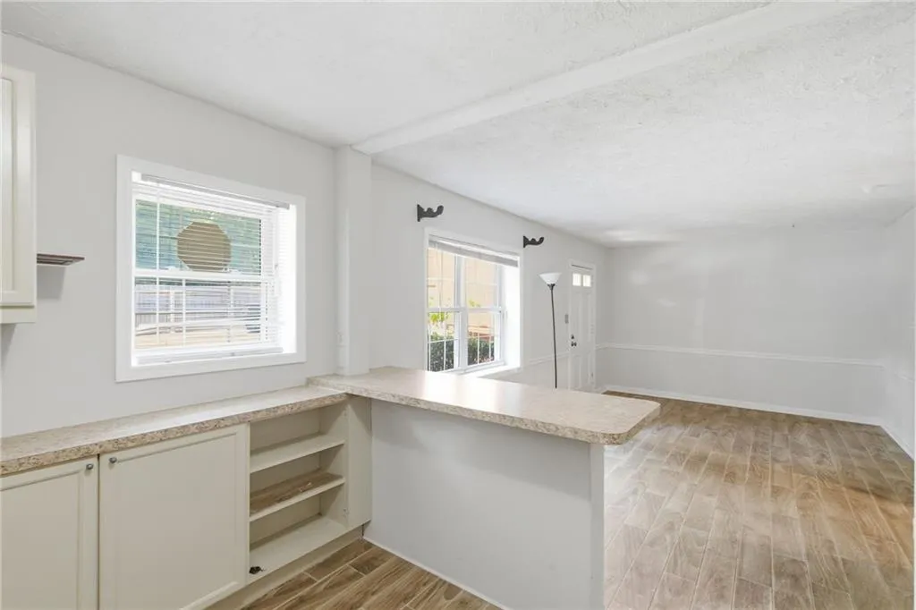 Wood-finish flooring throughout, bright white walls, and a built-in counter with open shelving
