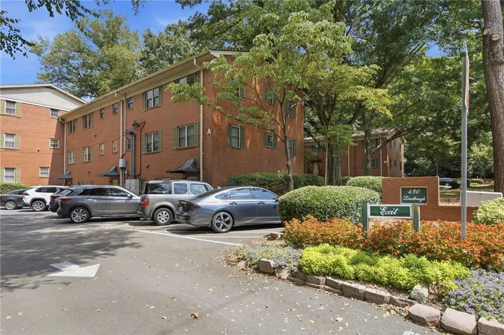 Brick exterior building with multiple windows, landscaping, parking lot, and mature trees