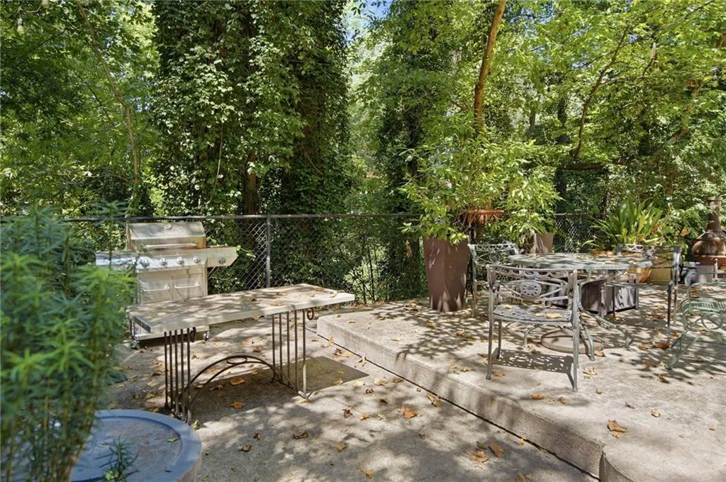 Expansive concrete patio area with a built-in grill station and privacy fencing