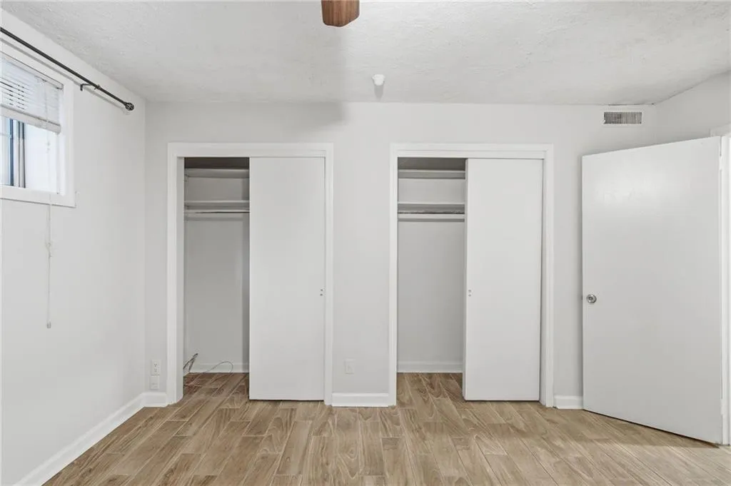 Wood-finish flooring, two sliding closet doors, and white walls