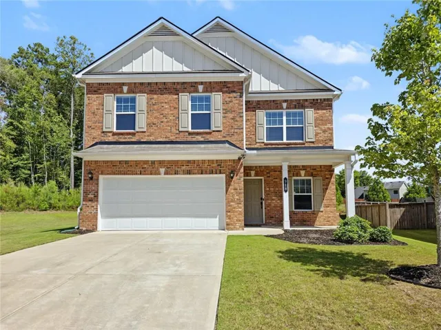 Brick-front exterior with a two-car garage, covered porch, and mature landscaping
