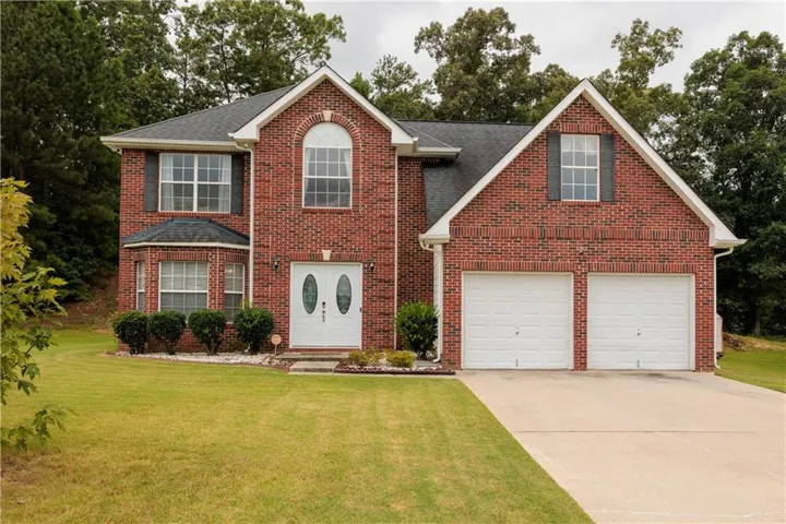Brick exterior with a peaked roofline, a two-car garage, and a curved bay window