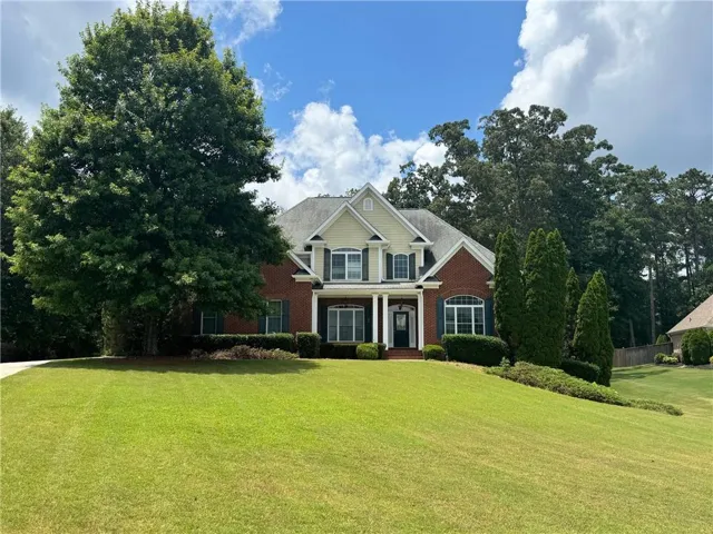 Traditional two-story residence featuring brick and siding facade, a gabled roofline, and a prominent front entrance with columns
