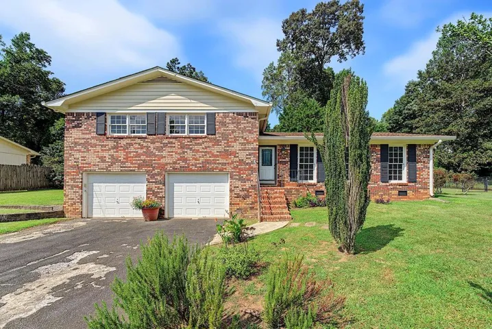 Brick facade with white trim, two-car garage, front entry with brick steps, and a landscaped front yard