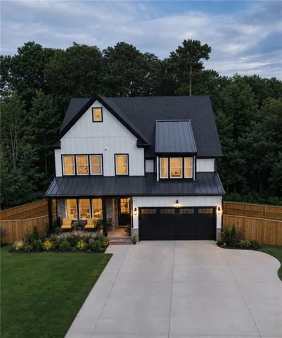 Modern farmhouse exterior with board and batten siding, dark trim windows, a covered front porch, an attached two-car garage, and a concrete driveway