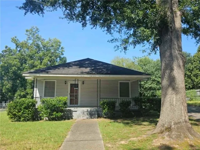 Siding exterior with a covered porch, established lawn, and mature trees