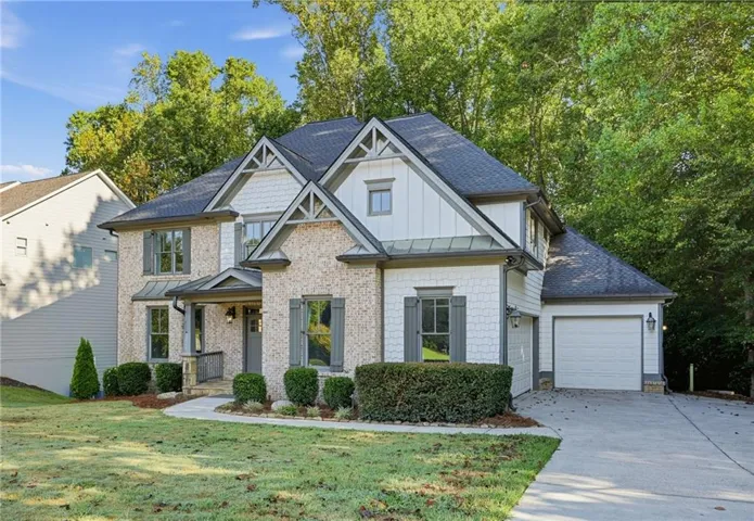 Craftsman-style home featuring a stone and siding exterior, multi-gabled roof, covered entry, attached garage, and concrete driveway
