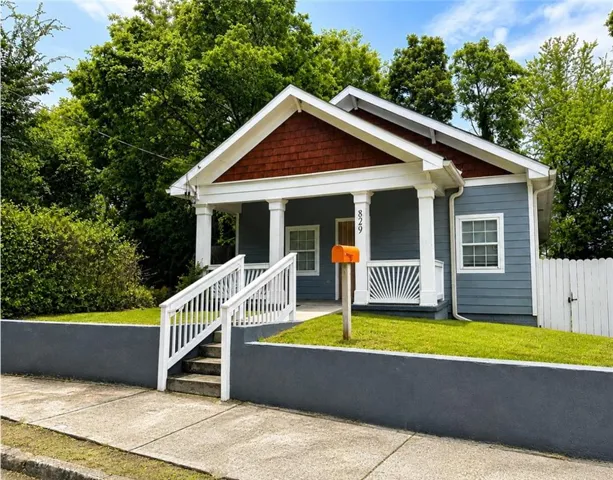 Exterior featuring siding, a front porch with white columns, a pitched roof with shingle accents, and a white picket fence
