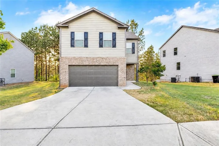 Two-story exterior with a two-car garage, brick and siding facade, and a concrete driveway