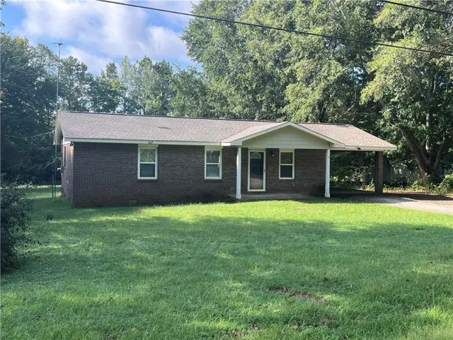 Brick exterior with white window frames, covered front porch, and an attached carport. One-level living at its finest! TRUE BRICK RANCH home on LARGE LEVEL lot!