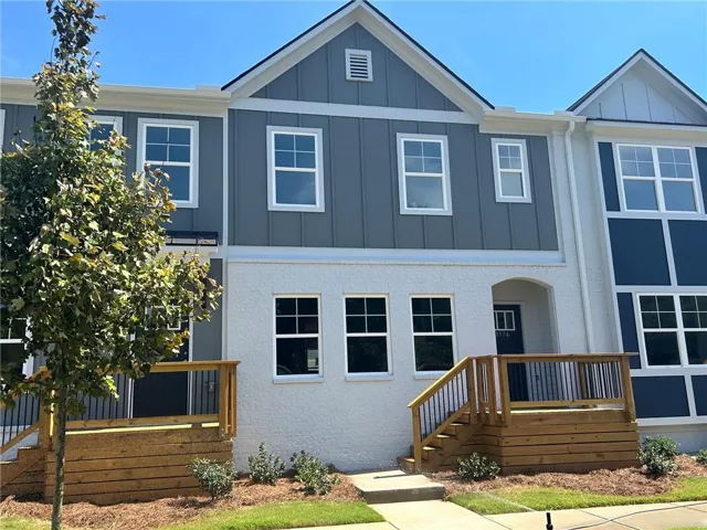 Multi-level facade with board and batten siding, stucco finish, and white-framed windows