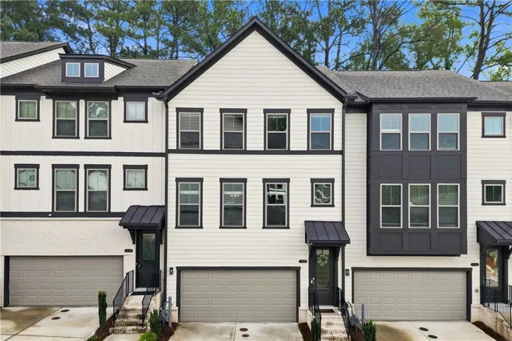 Contemporary townhome featuring a multi-tone facade, prominent gabled roofline, multiple windows, and covered entryways