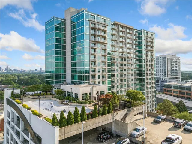 View of apartment building / complex featuring a view of city and uncovered parking