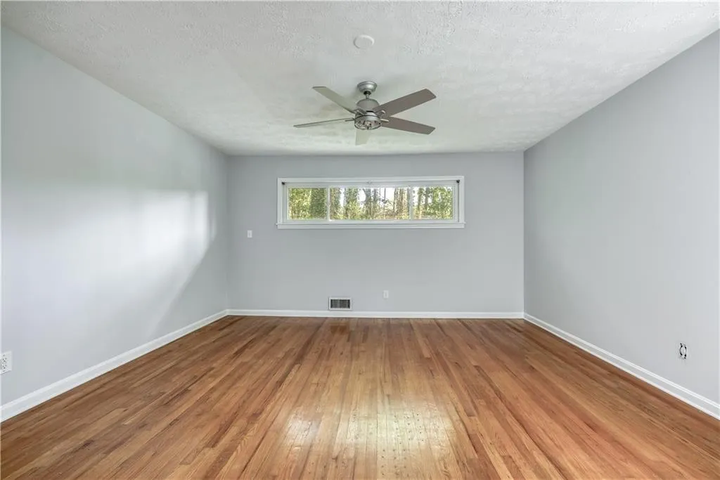 Empty room with ceiling fan, a textured ceiling, and hardwood / wood-style flooring
