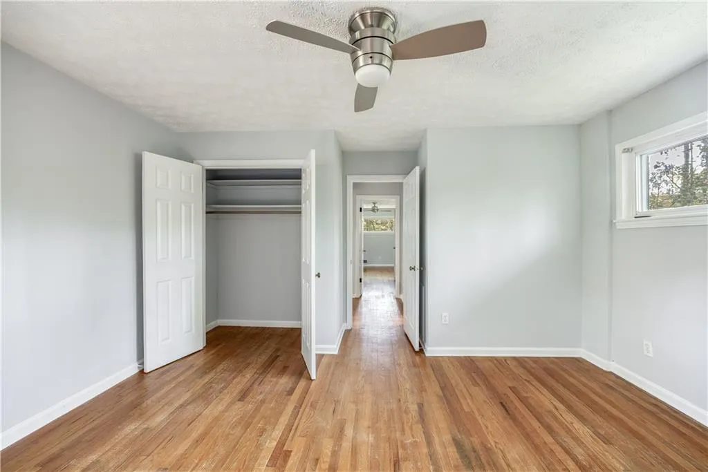 Unfurnished bedroom with a closet, a textured ceiling, ceiling fan, and light wood-type flooring