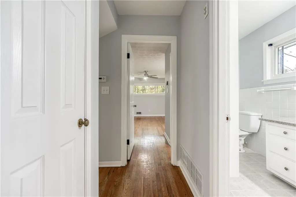 Hallway featuring tile walls, light wood-type flooring, and a wealth of natural light