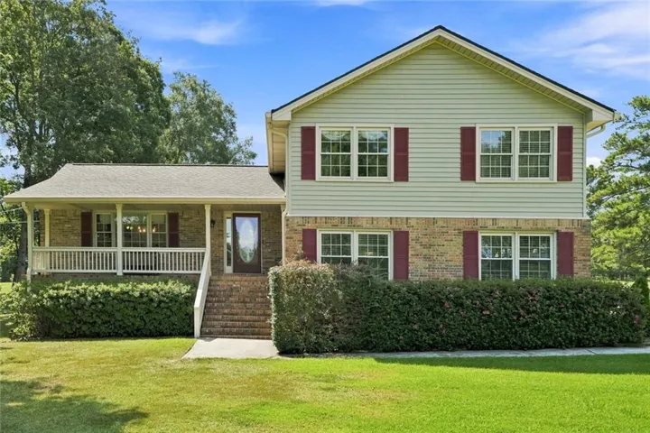 Two-story exterior with brick and siding, covered front porch, brick stairs, and mature landscaping