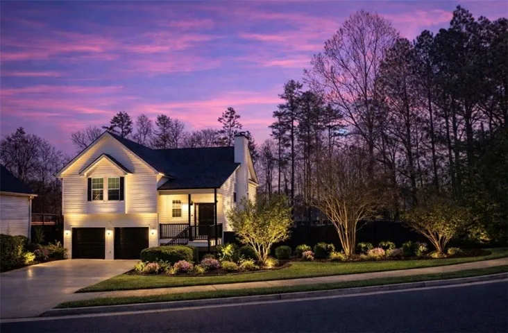 View of front of property featuring an attached garage, a chimney, driveway, covered porch, and a front yard