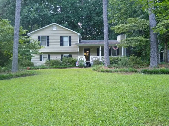 Two-story residence with siding exterior, black window shutters, a covered porch, and a gable roofline