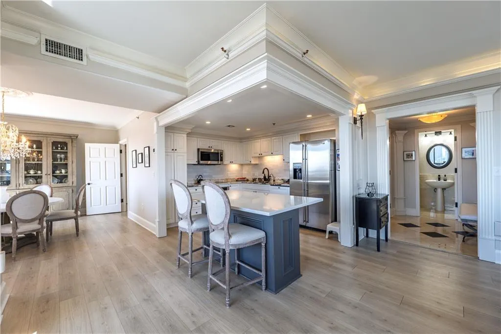 Kitchen with appliances with stainless steel finishes, light wood-type flooring, visible vents, and crown molding