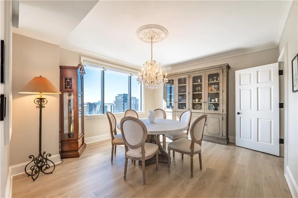 Dining space with a chandelier, light wood-type flooring, ornamental molding, and a view of city