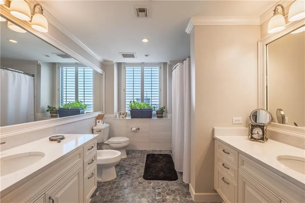 Bathroom featuring ornamental molding, two vanities, visible vents, and a sink
