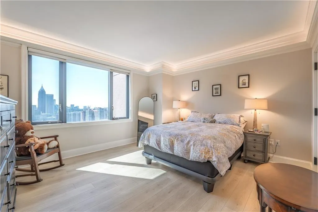 Bedroom featuring light wood-type flooring, crown molding, baseboards, and a city view